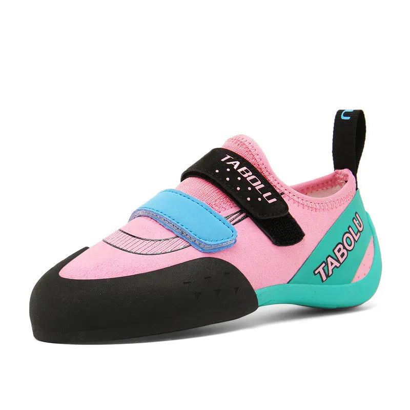 Beginner rock climbing shoes with Velcro straps and a coloured rubber sole on a climbing hold.