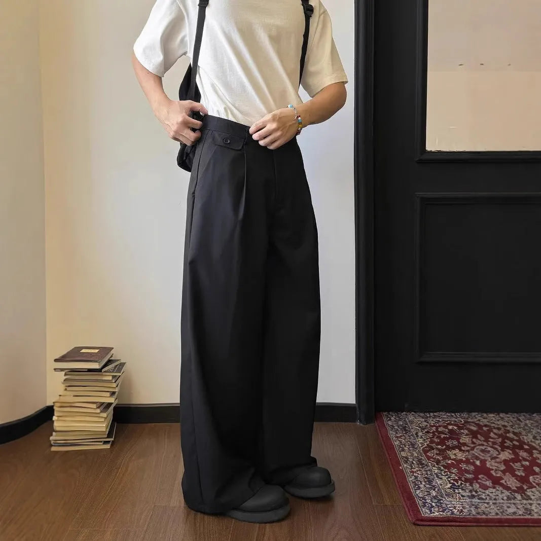 Men's brown straight-leg wide-drape trousers on a hanger, showing loose fit.