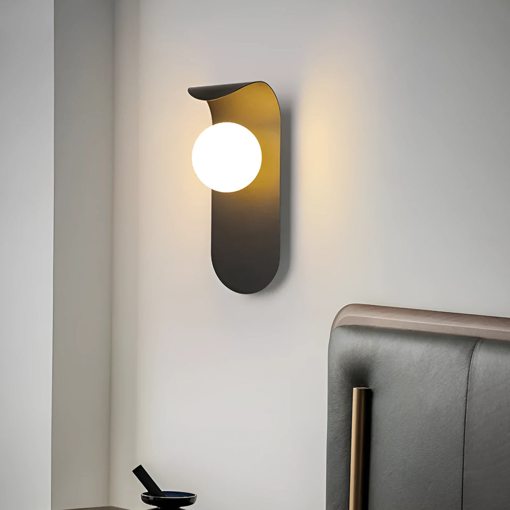 Modern minimalist black wall lamp with iron shade and LED light on a bedroom wall
