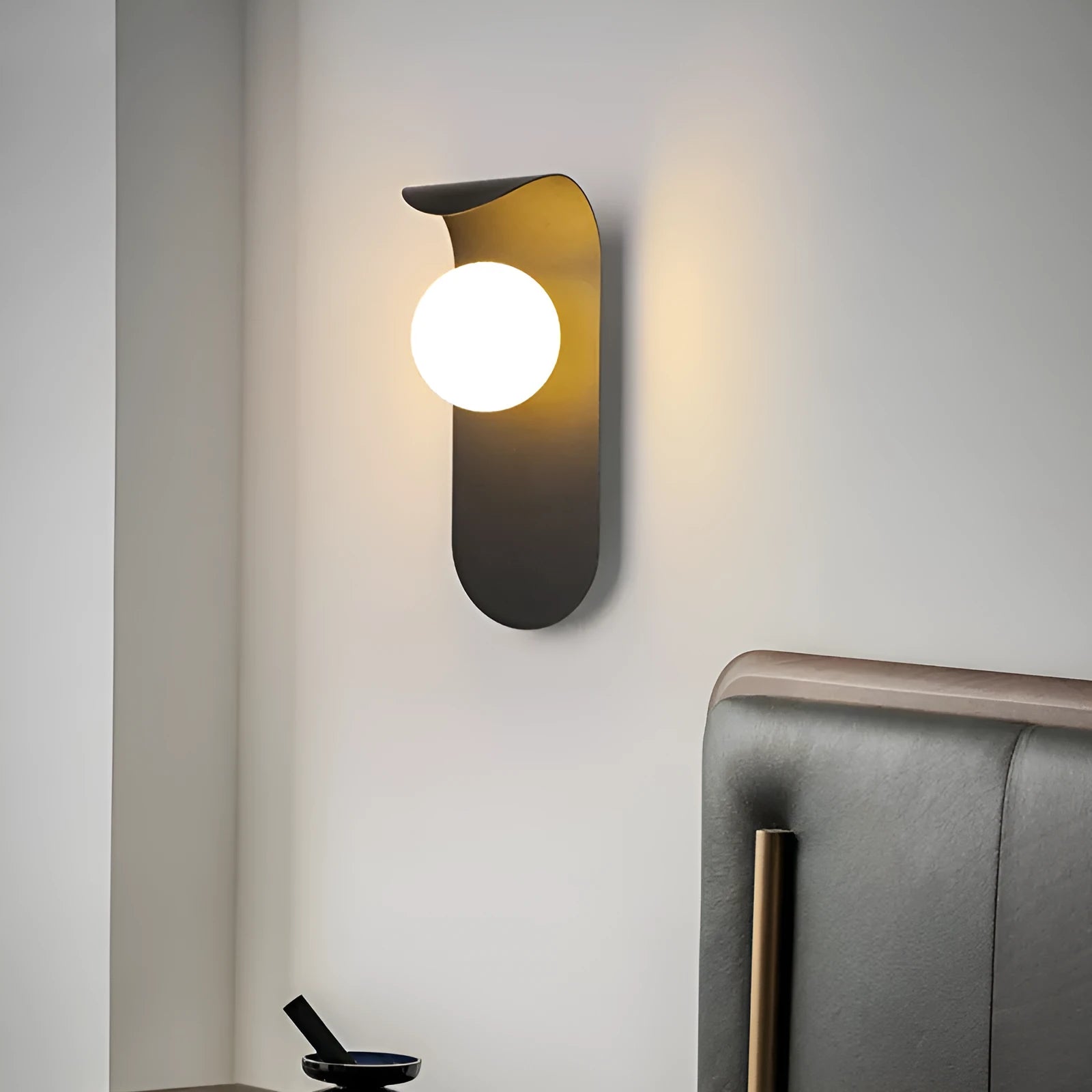 Modern minimalist black wall lamp with iron shade and LED light on a bedroom wall
