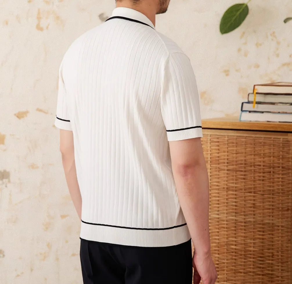 Man wearing a slim fit black knitted polo shirt with a lapel collar and short sleeves.
