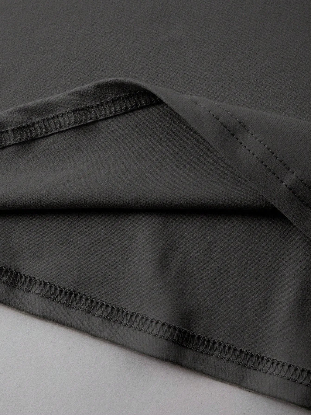 A loose-fitting black cotton T-shirt with short sleeves and a round neck on a hanger.