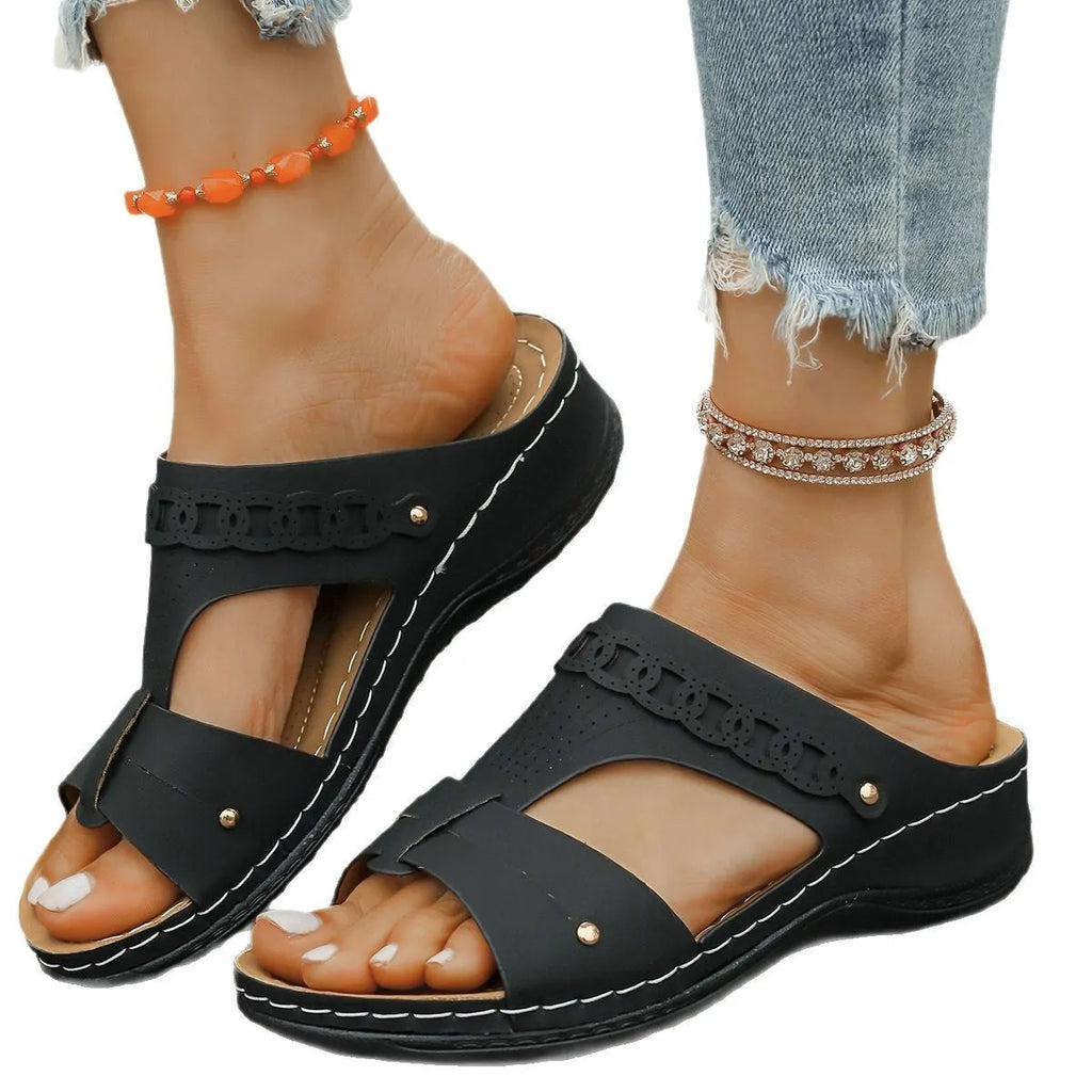 Women's beige Roman style slippers with a slope heel and fish mouth toe holder on a rubber sole.