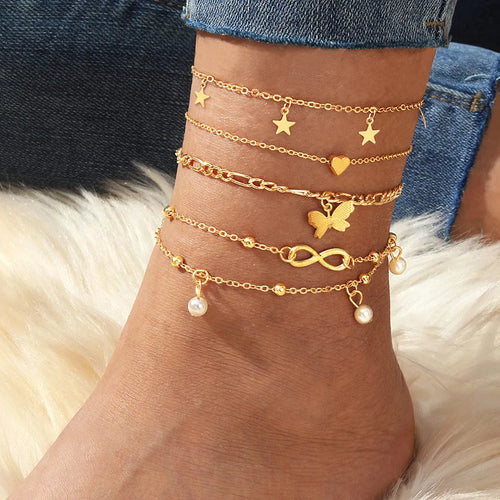 Four gold-tone alloy anklets with butterfly and heart pearl charms arranged as a set