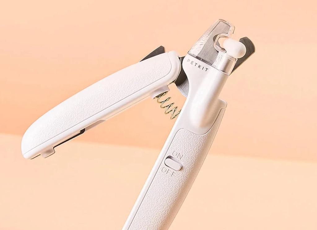 White LED pet nail clipper with a triangular blade, anti-splash guard, and leatherette handle.