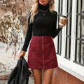 Women's high waist short skirt in black with contrast stitching and side zipper, shown on a model.