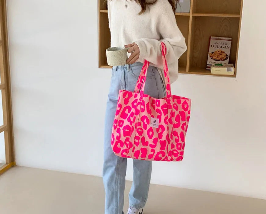 Large pink women's canvas shoulder bag with a textured three-dimensional front pocket.