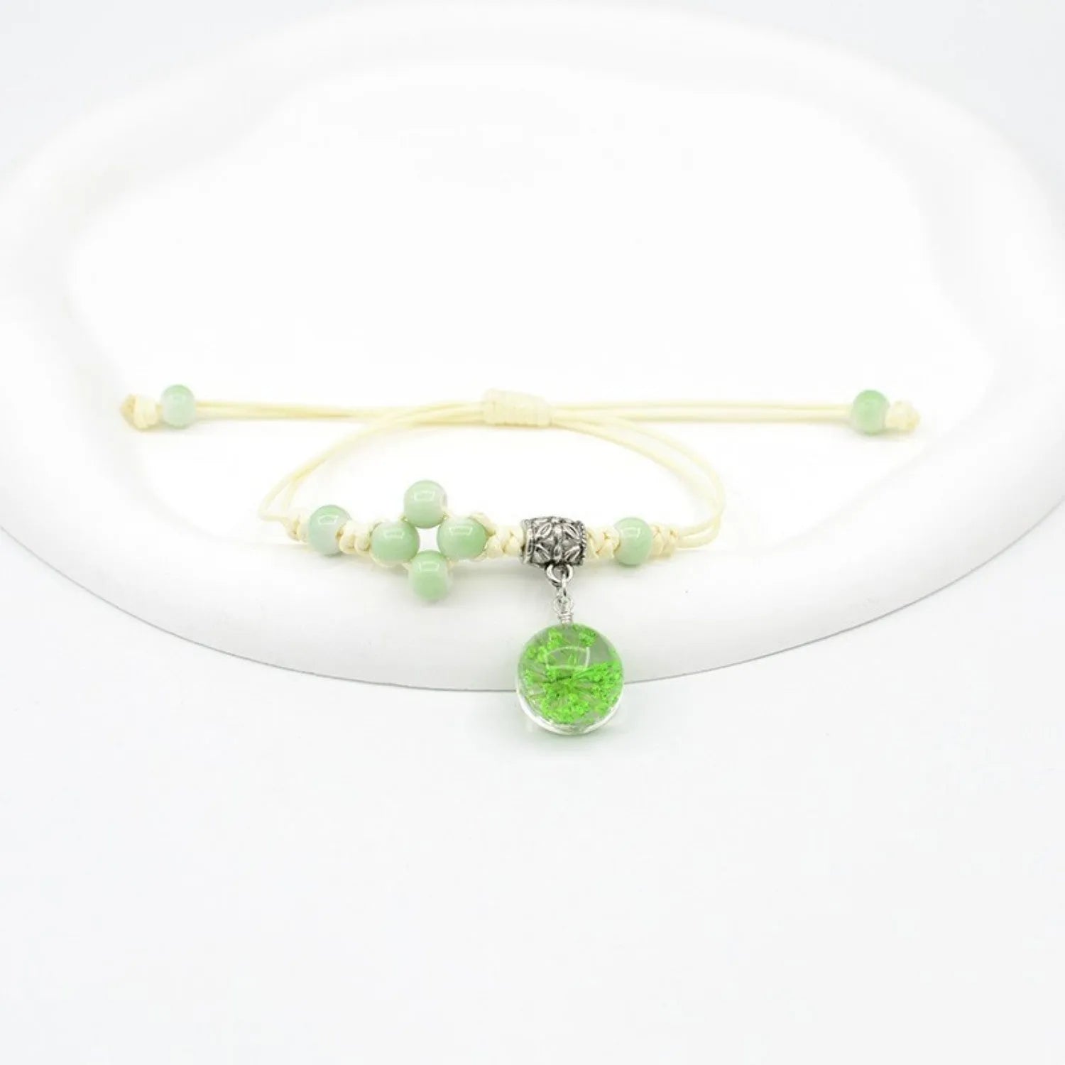 Close-up of a hand-woven glass bracelet with large beads containing real dried flowers and a lace design.