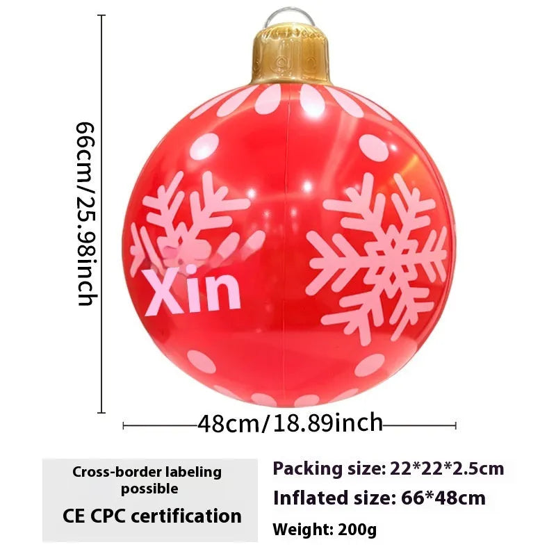 Large red and white inflatable Christmas ball with flashing lights in a garden setting.