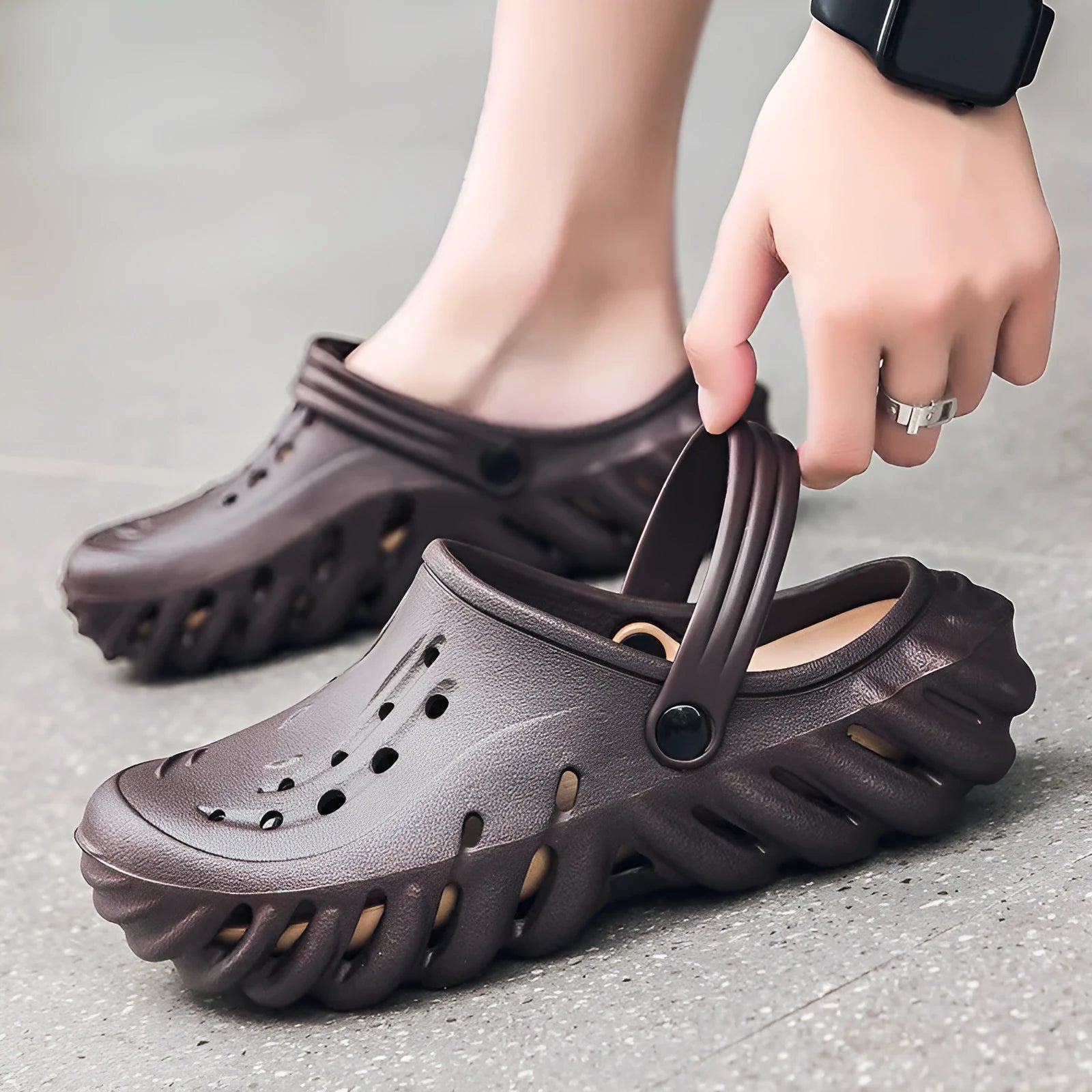 Men's beige EVA slipper sandals with hollow-out design and non-slip sole, shown on a wooden deck.