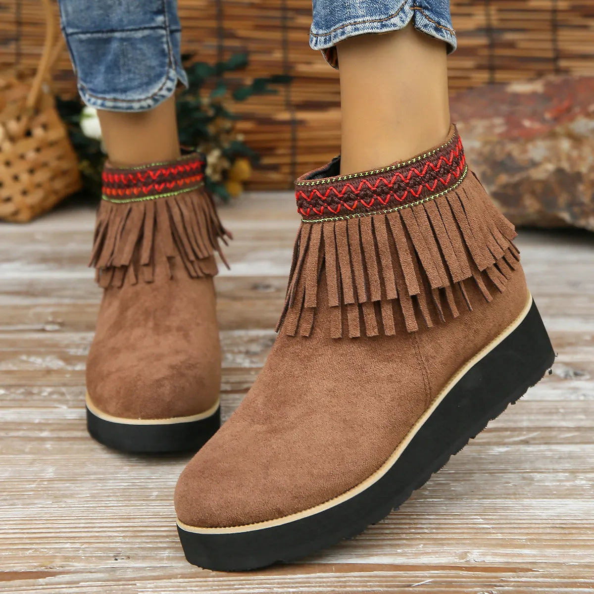 Women's suede ankle boots with a wedge heel, side zipper, tassel detail, and thick rubber sole.