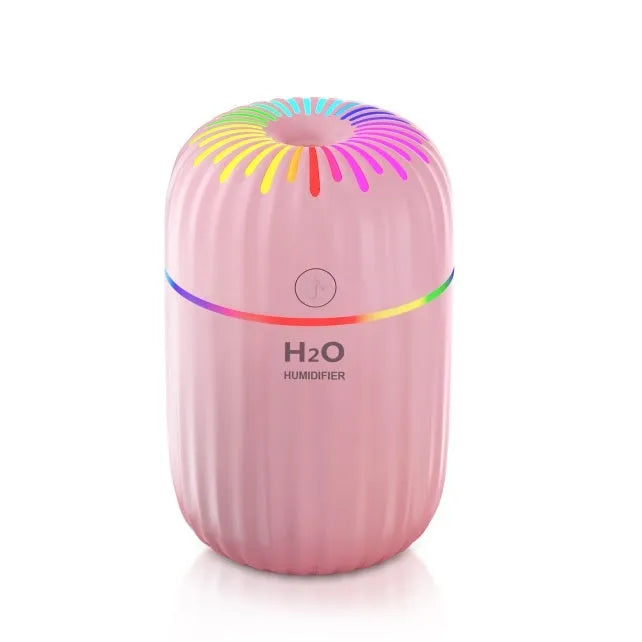 Small white USB personal humidifier with water tank on a wooden desk.