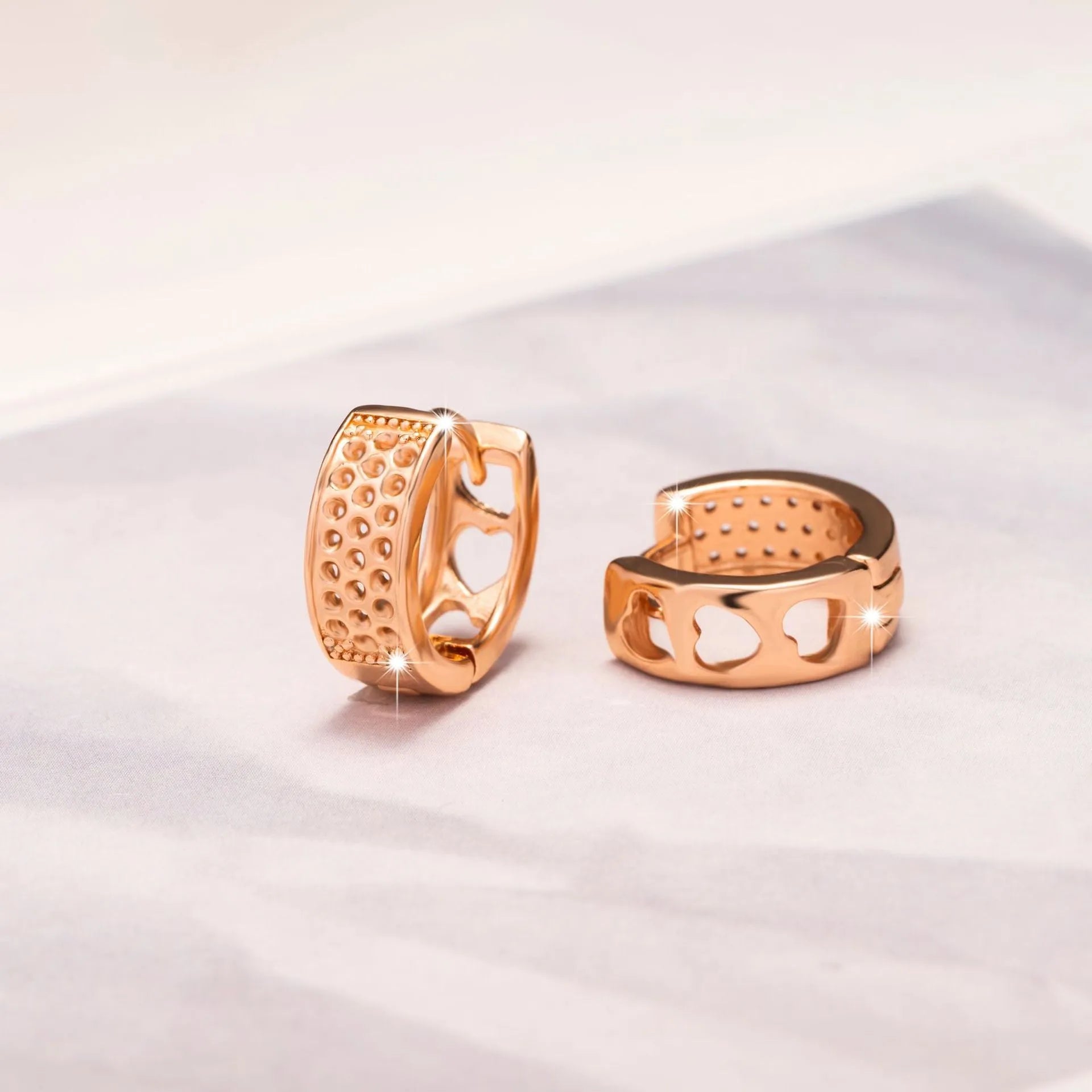 A pair of rose gold hollow heart-shaped earrings for women on a white background.