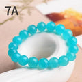 Natural blue-green Amazonite polished beads scattered on a surface, with a finished crystal bracelet.