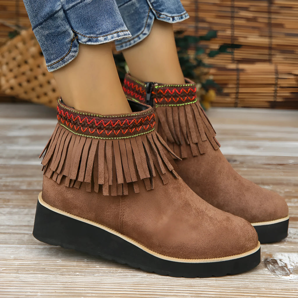 Women's suede ankle boots with a wedge heel, side zipper, tassel detail, and thick rubber sole.