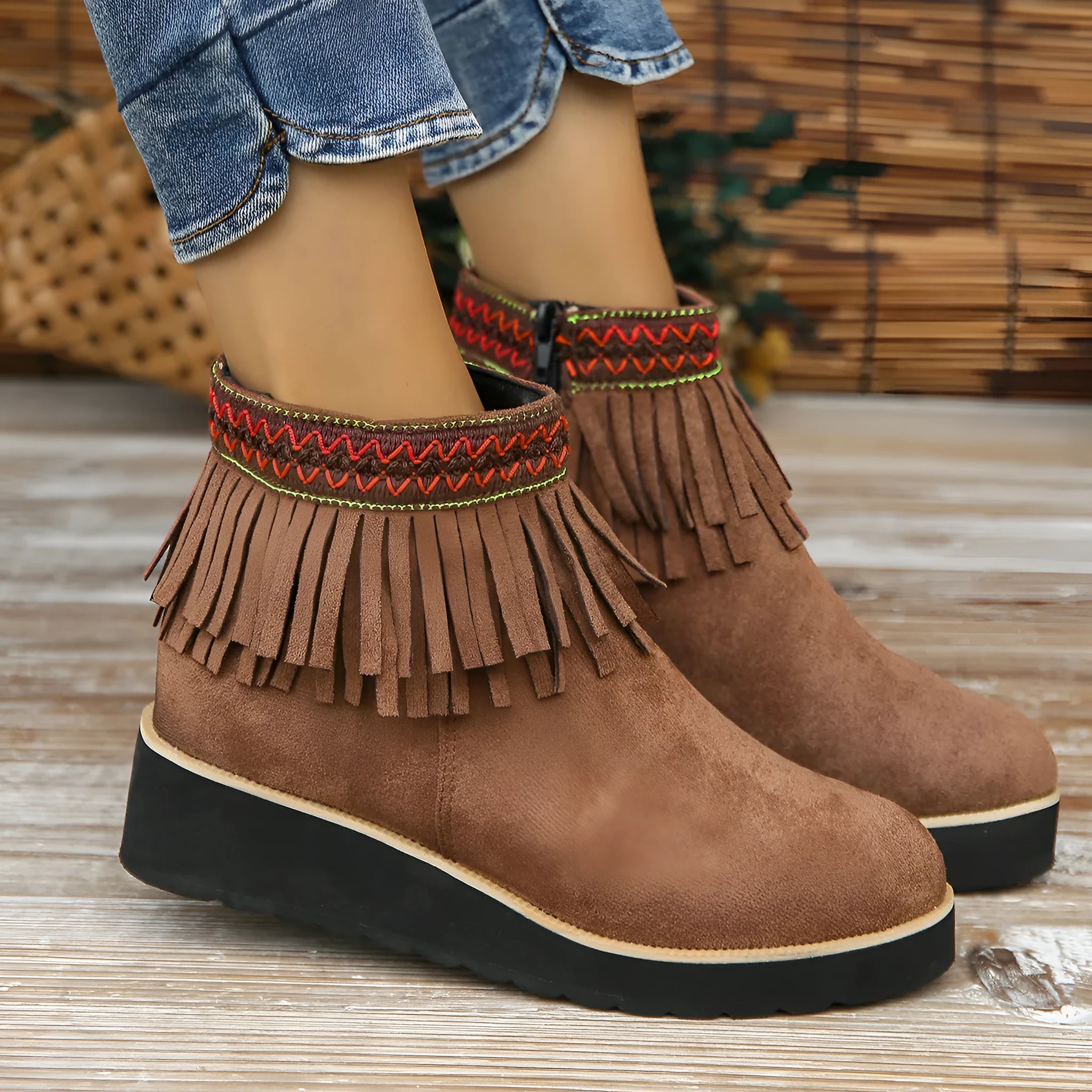 Women's suede ankle boots with a wedge heel, side zipper, tassel detail, and thick rubber sole.
