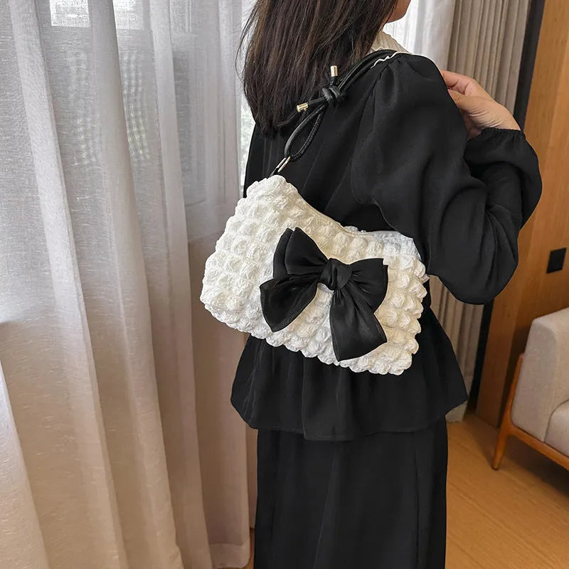Women's horizontal square canvas handbag with single shoulder strap in black colour showing internal phone pocket