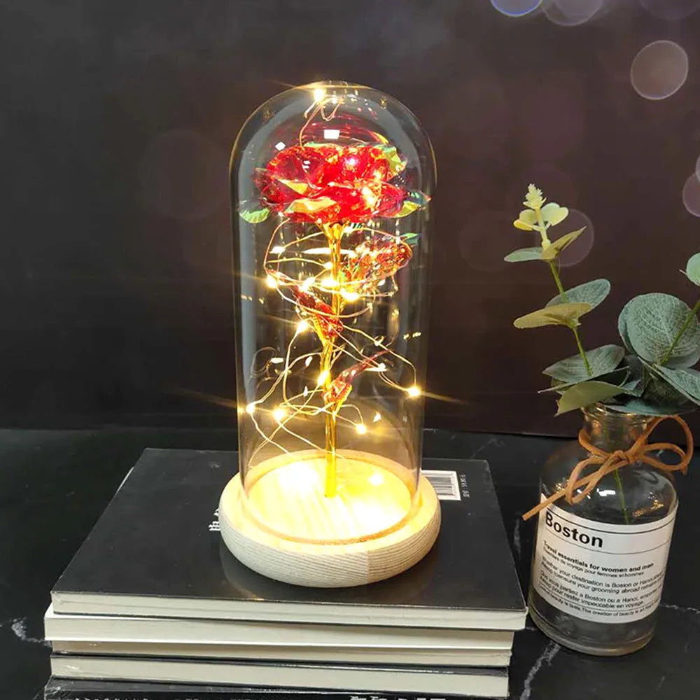LED illuminated silk rose bouquet in a glass dome on a wooden base, with warm white lights.