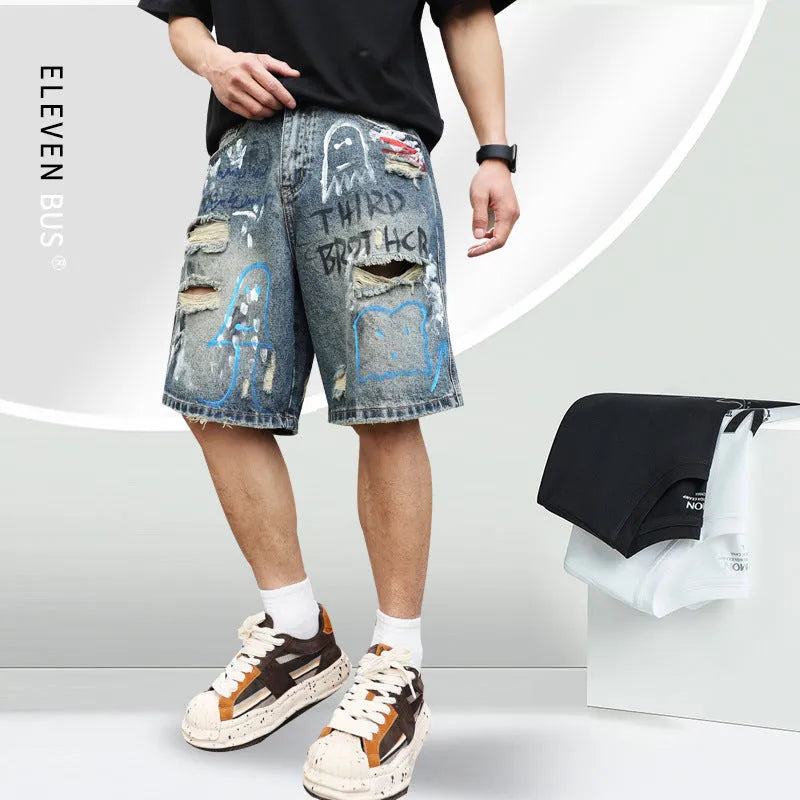 Blue men's ripped denim shorts with graffiti detailing and a straight-leg cut, showing front zipper fly.
