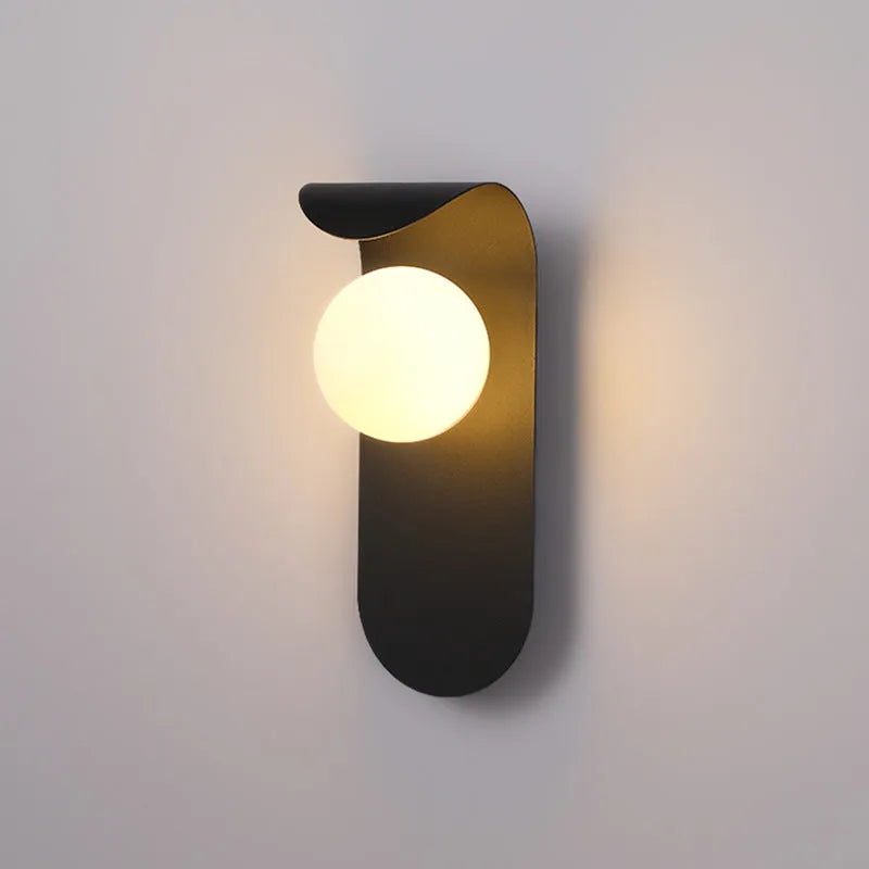 Modern minimalist black wall lamp with iron shade and LED light on a bedroom wall