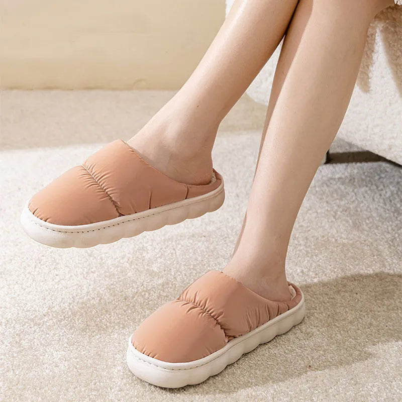 Pair of thick-soled indoor slippers in blue with a wrapped toe, low heel, and artificial plush lining.