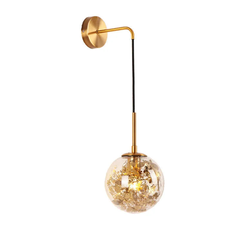 Simple modern glass wall lamp in golden flower finish mounted beside a bed.