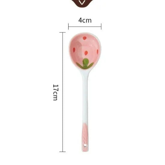 Cute strawberry pattern porcelain dinnerware set showing bowl, plate, and twist spoon on a table.