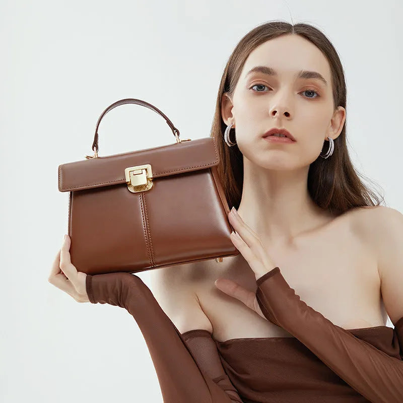 Women's black leather shoulder bag with vachette clasp, showing horizontal square shape and adjustable strap
