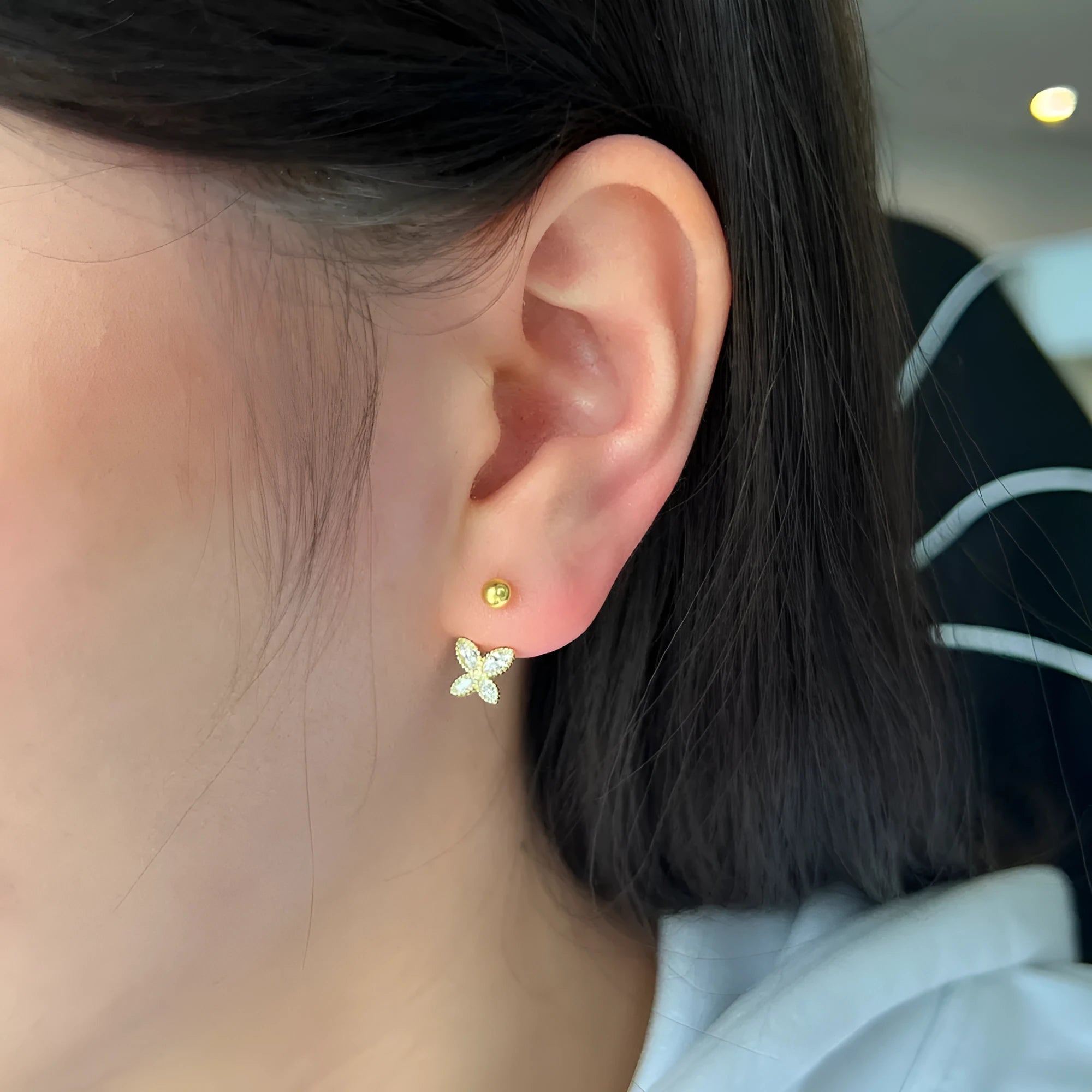 Pair of S925 silver bow-shaped ear hook earrings in gold finish on simple background