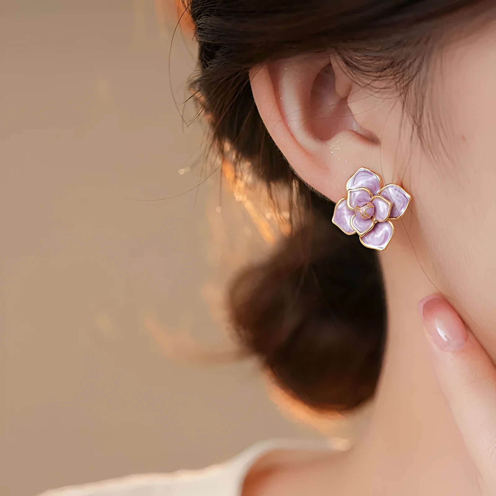 Close-up of a pair of purple and gold flower stud earrings with a textured oil-spot glaze finish.