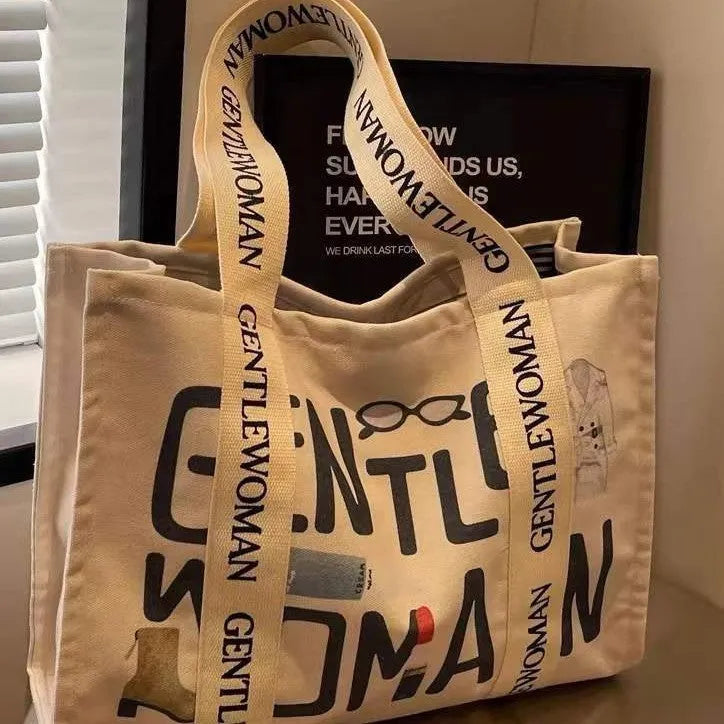Large canvas tote bag with printed design, featuring two fabric handles, shown in available colour style options.
