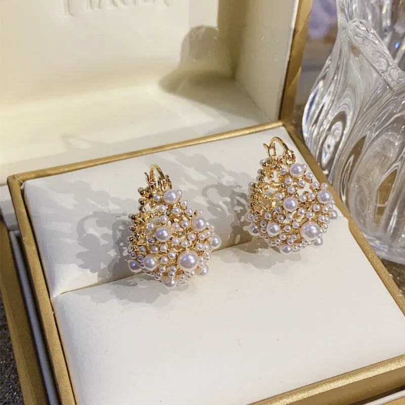 Gold-coloured copper flower basket earrings with small rice-shaped beads and pearl inlay detail.