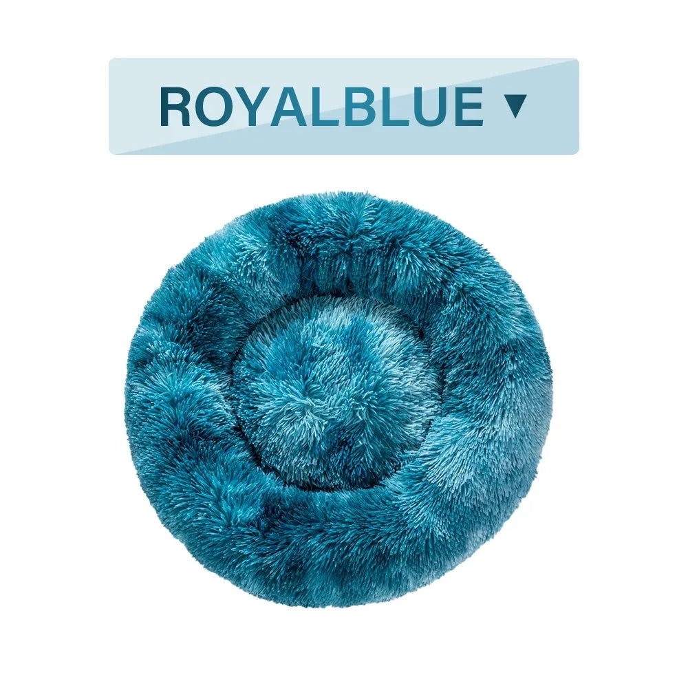Fluffy donut-shaped dog bed in long plush material, shown in a light grey colour.