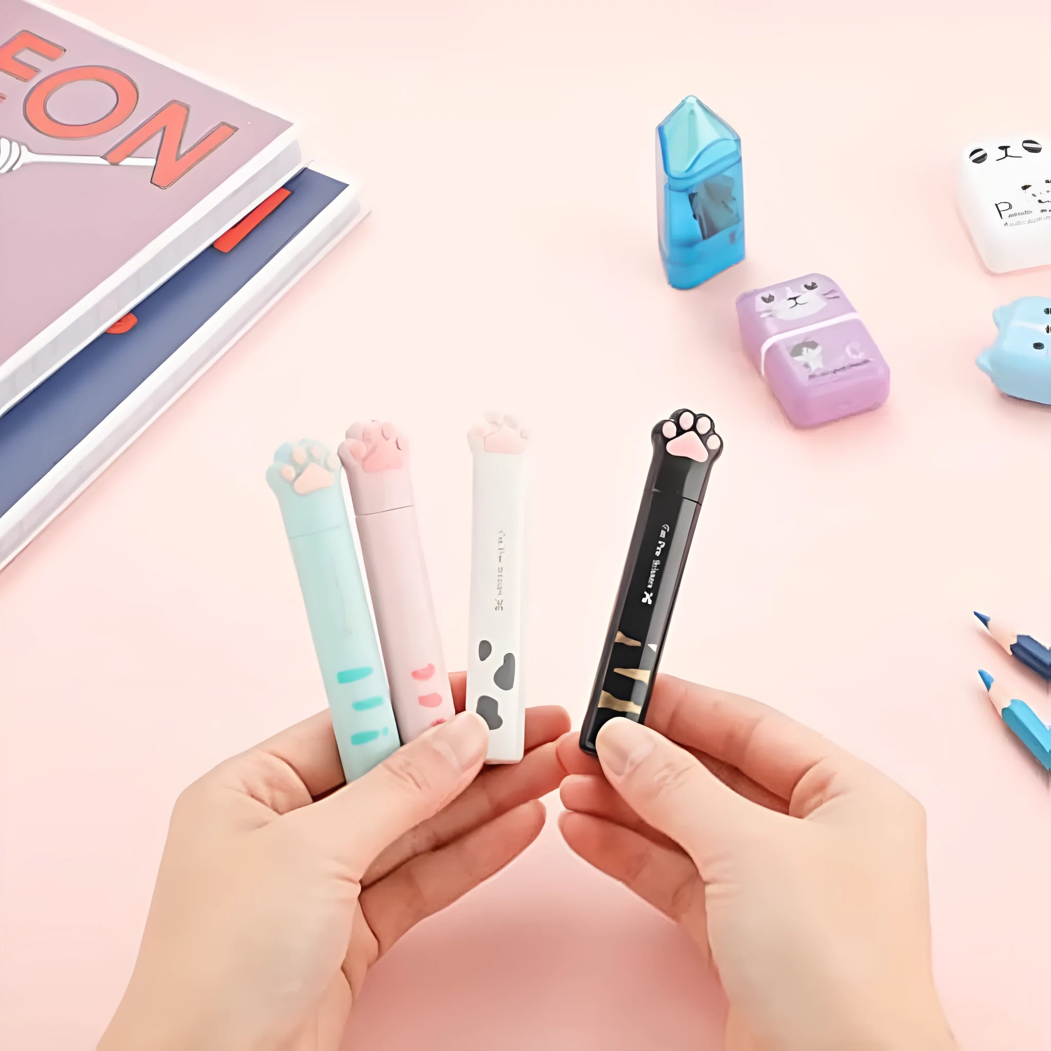 Small stainless steel folding scissors with cat paw handles shown in pink, blue, black, and white.