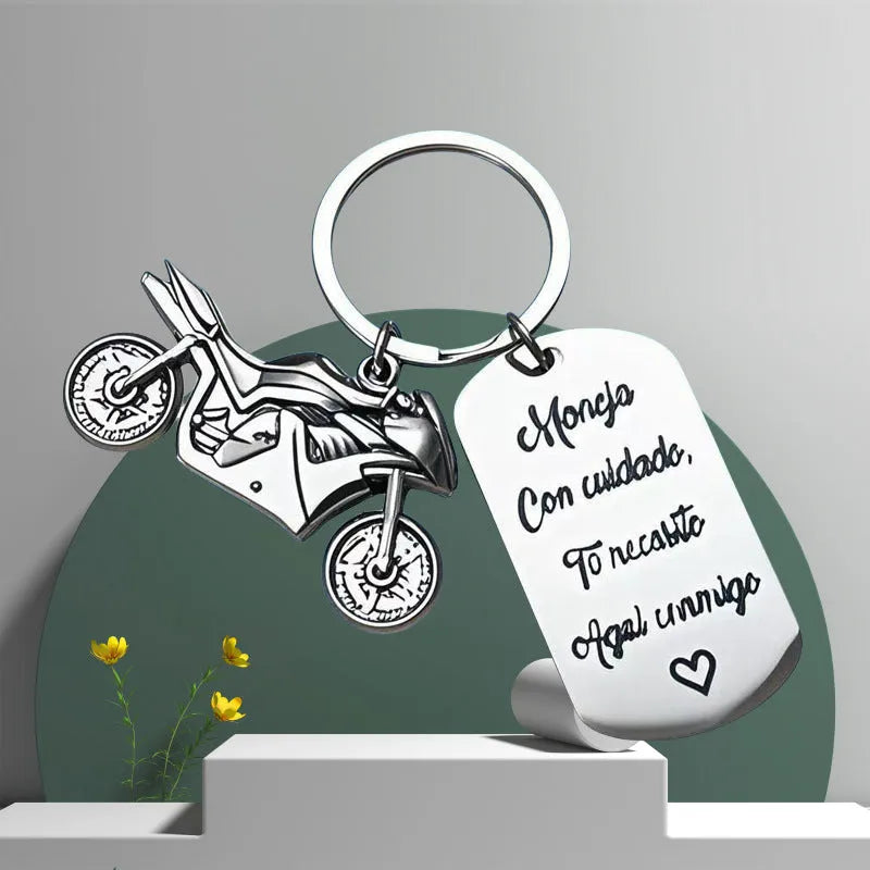 Stainless steel motorcycle keychain with a dark flannel storage pouch on a grey background.
