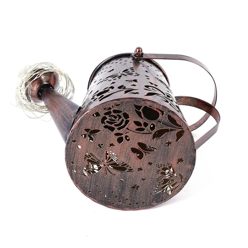 Tapered iron solar garden lantern with butterfly pattern emitting warm white light.