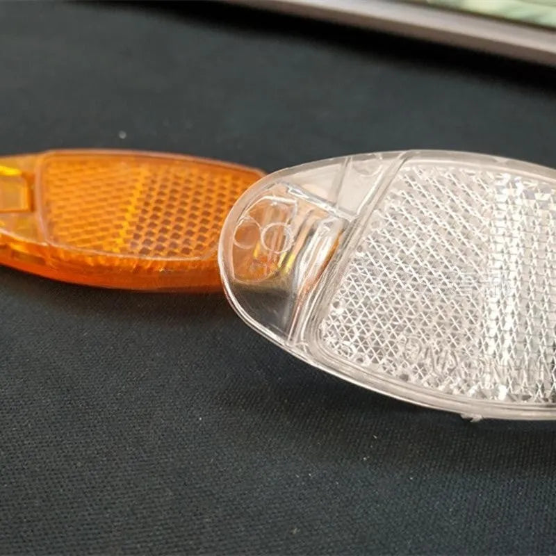 White and yellow plastic bicycle reflector stickers for spoke mounting measuring 7.2cm by 3.5cm