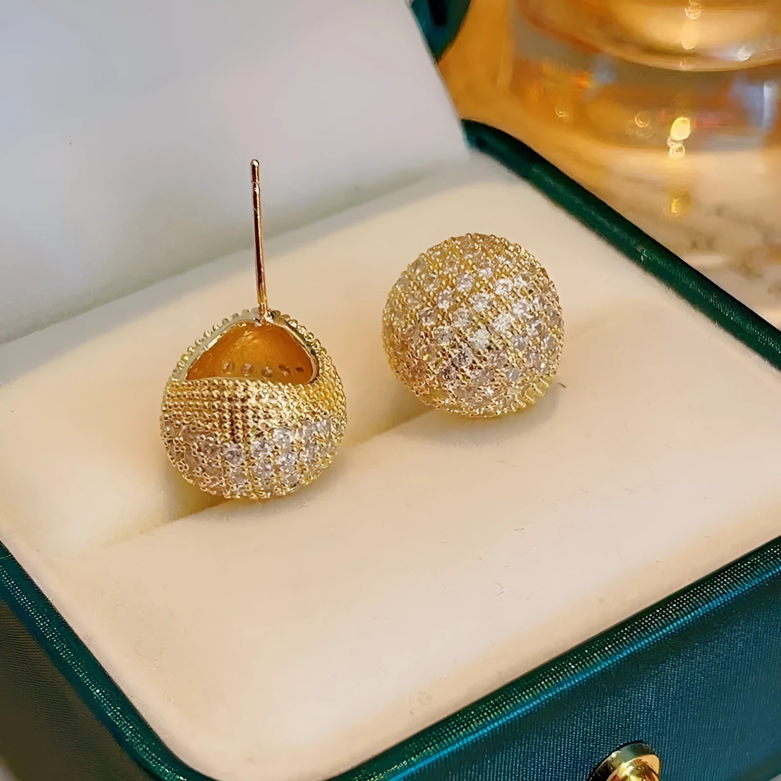 Drop-shaped geometric golden beans and diamond ear clip earrings in gold and white colours.