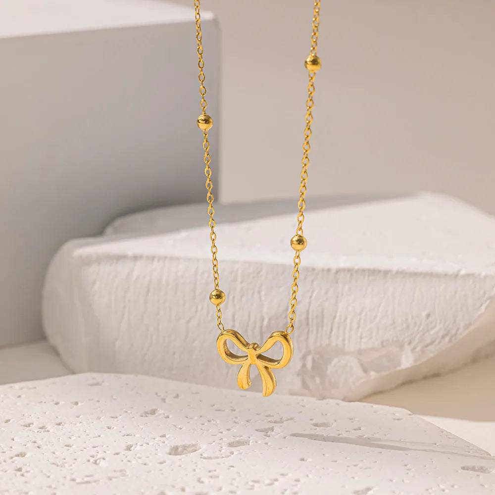 Gold electroplated bow pendant fashion necklace on a cross chain, adjustable 41-50cm.