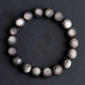 Obsidian crater ball bracelet with textured meteorite-like beads on elasticated cord