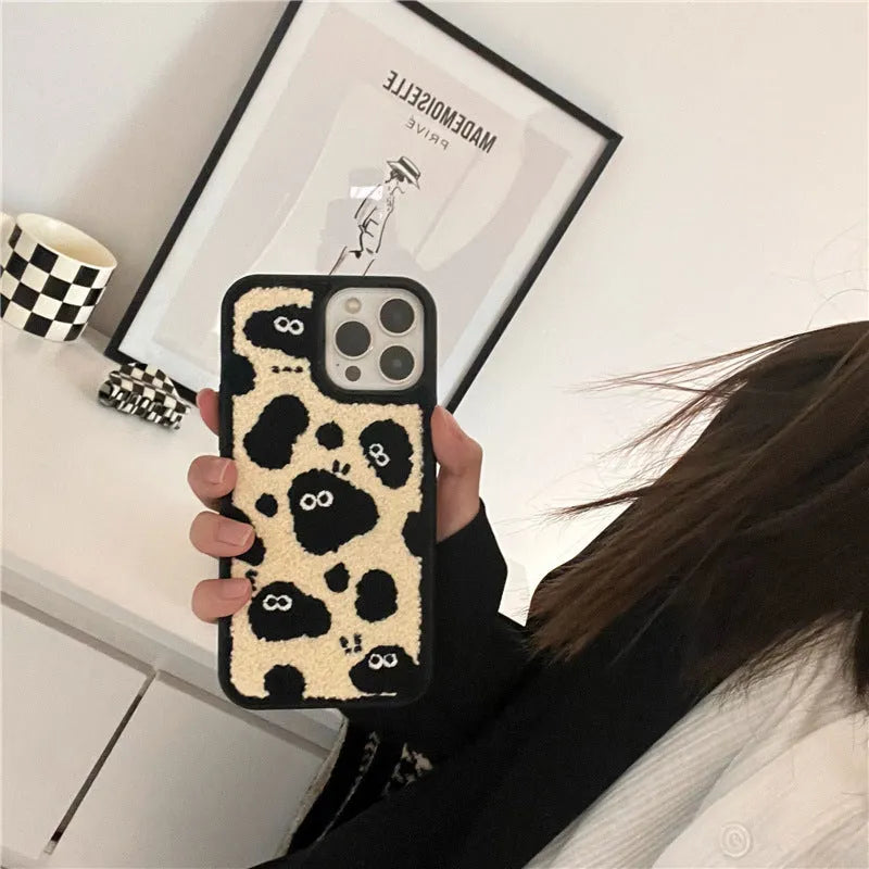 Black plush fairy funny back cover phone case for iPhone models on a table.