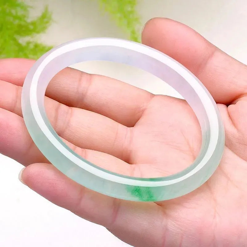 Jade bracelet with carved floating flower and auspicious cloud pattern in emerald green.