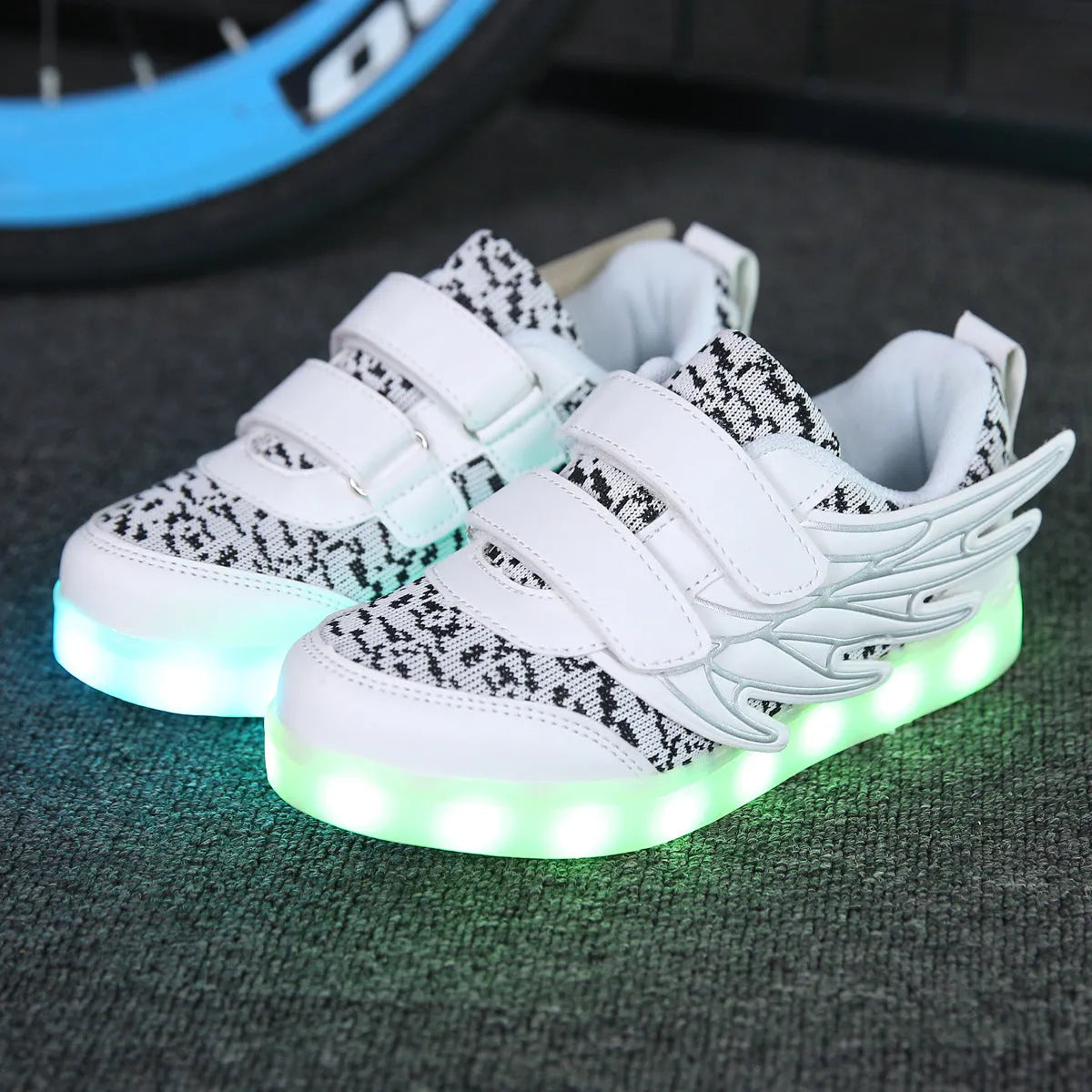 Plum red children's sneakers with LED lights glowing on the soles, showing USB charging port.