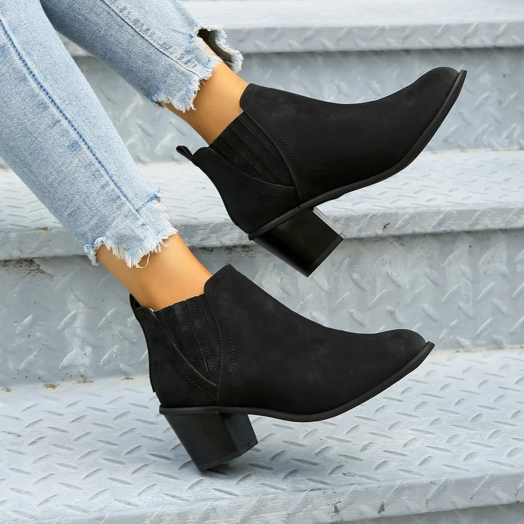 Women's black ankle boots with pointed toe and thick square heel on a rubber sole