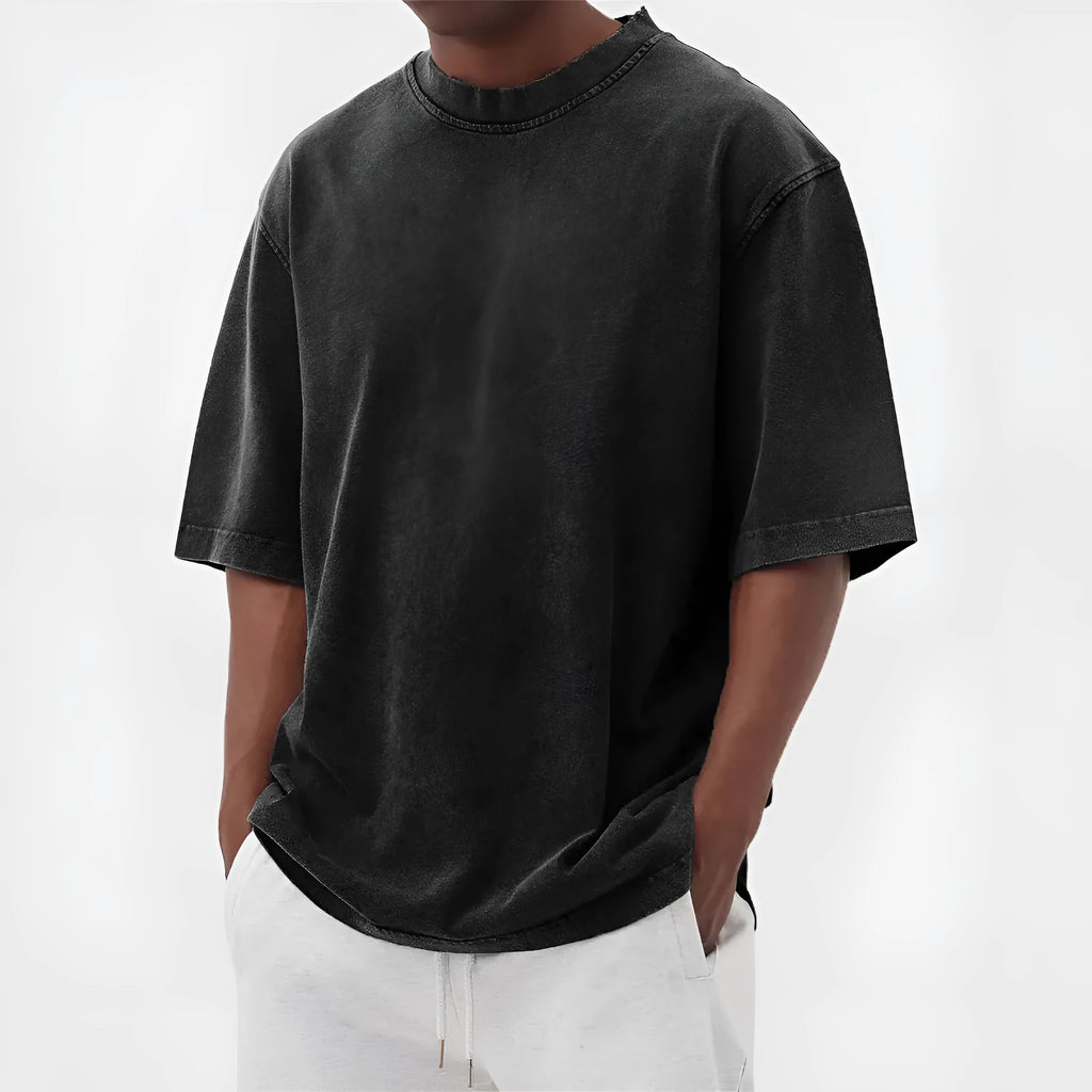 Man wearing a loose-fit, stone-washed polyester T-shirt in a solid colour with a distressed finish.