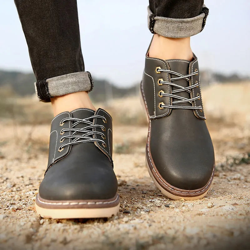 Men's black mid-top British style leather boots with a flat rubber sole.
