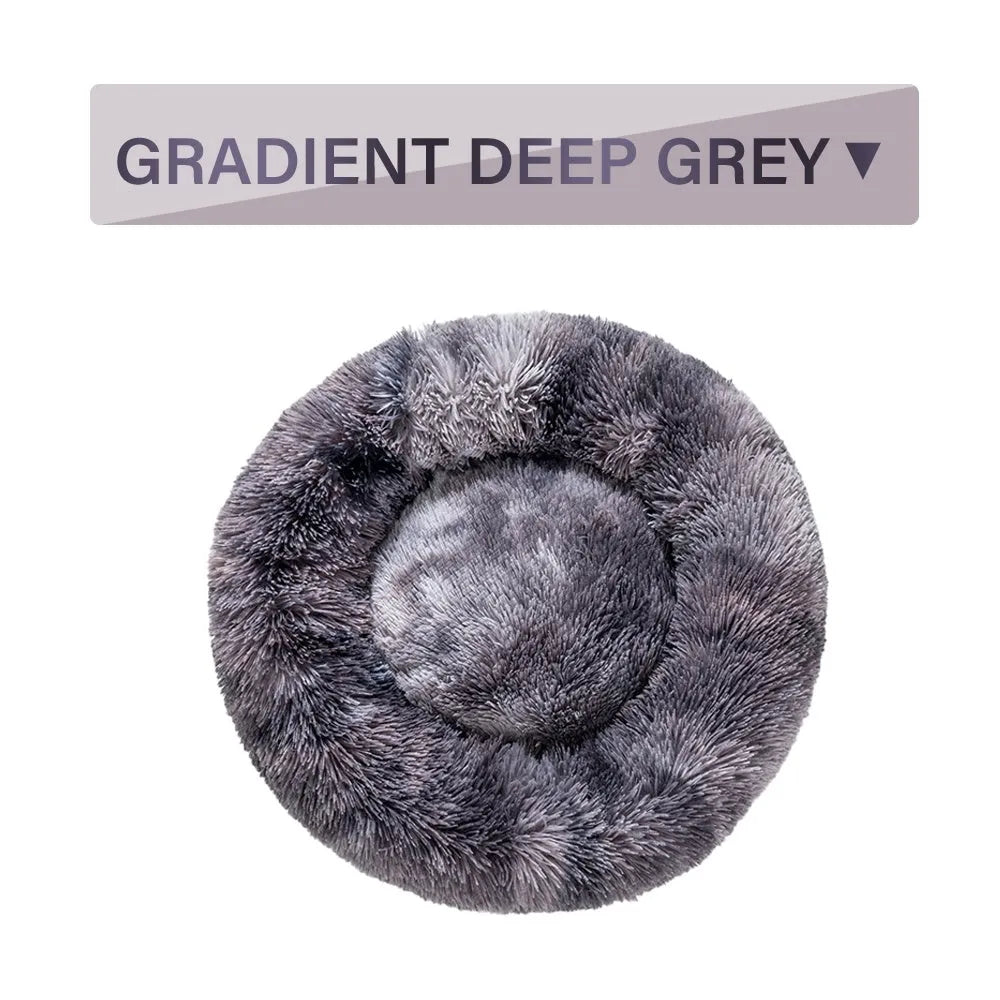 Fluffy donut-shaped dog bed in long plush material, shown in a light grey colour.