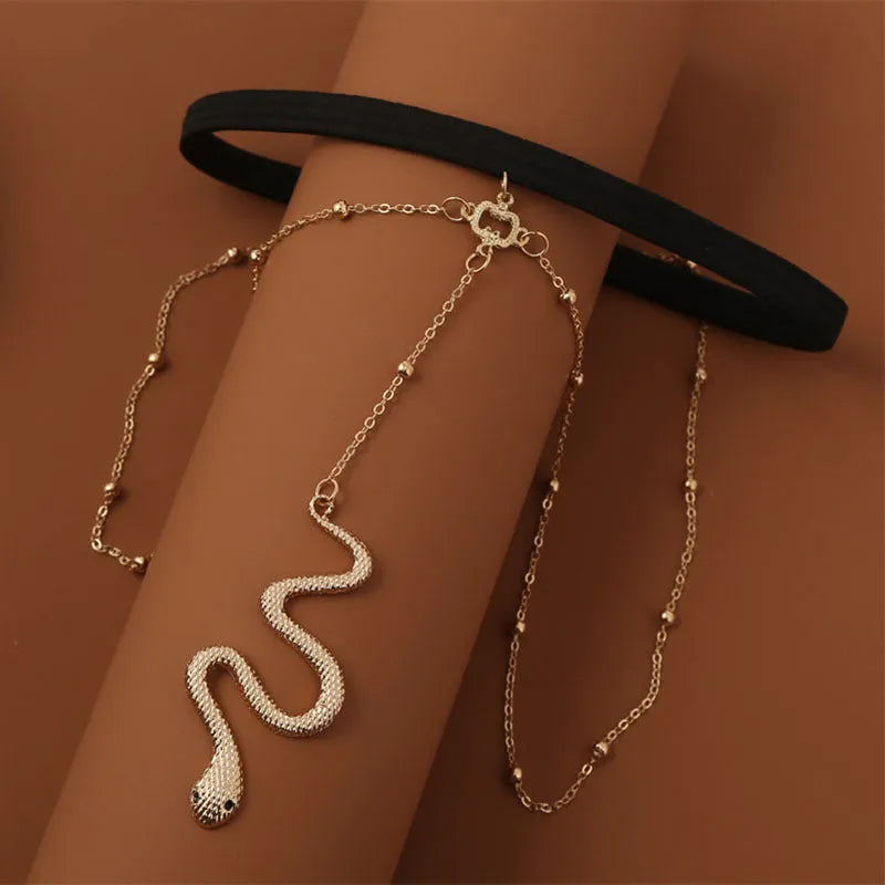 Gold metal beaded thigh chain with large snake pendant and artificial gem inlay, worn on a woman's leg