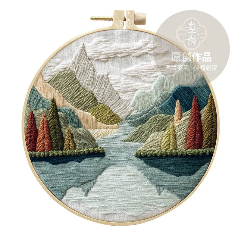 Embroidery DIY kit with bamboo frame, cotton fabric printed with a landscape scene, threads, and needles laid out