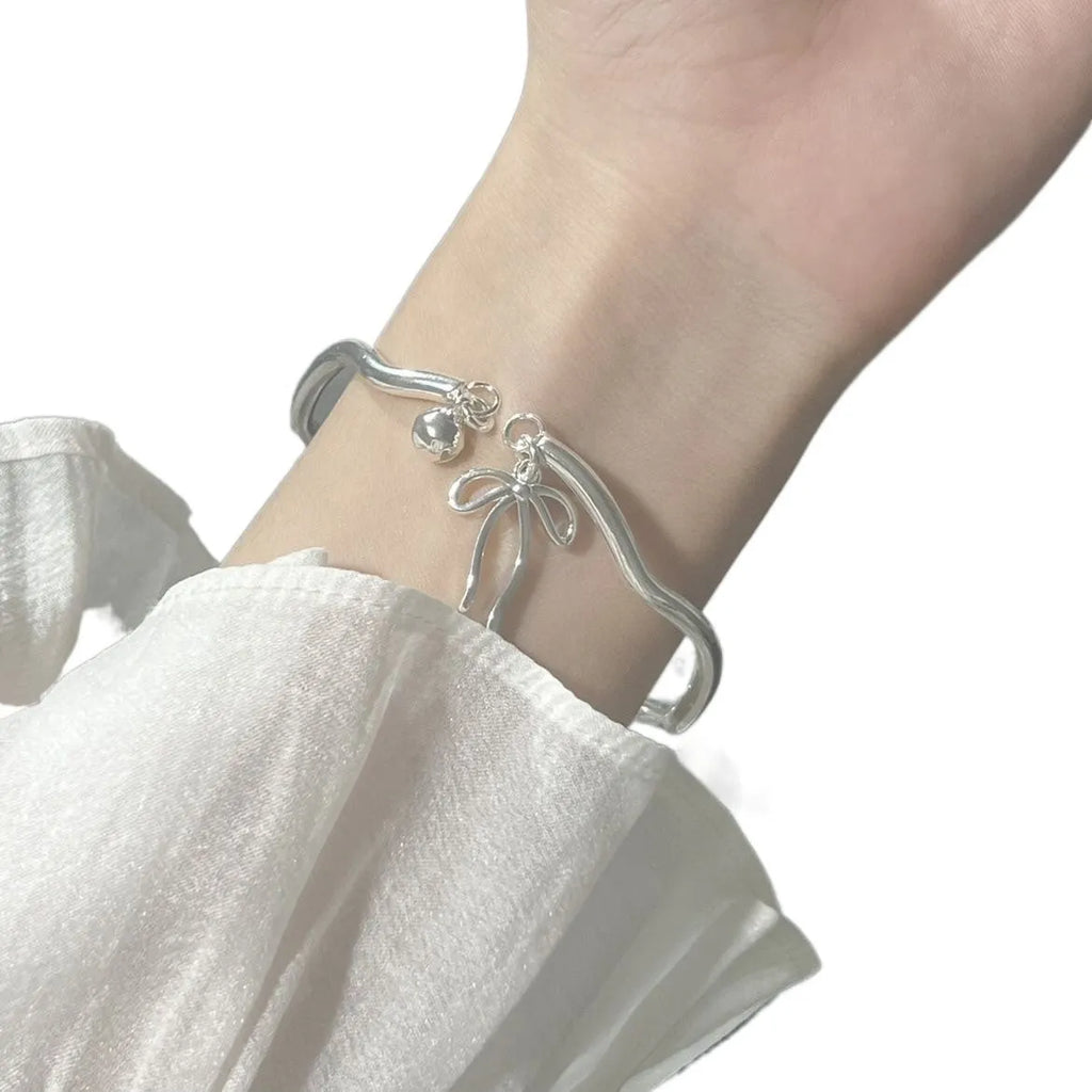 Silver bow charm adjustable bracelet with electroplated finish and bell opening mechanism